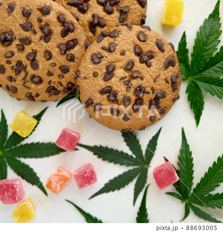 American cookies with cannabis extract. Sweets with CBD oil. Marijuana leaves on white background American cookies with cannabis extract. Sweets with CBD oil. Marijuana leaves on white background 88693005