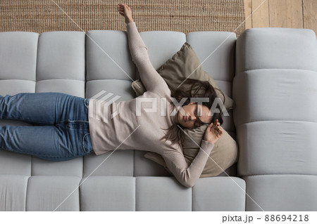 Sleepy girl in casual clothes resting on couch at home 88694218