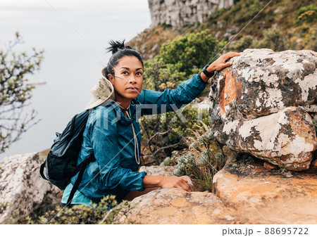 Female tourist doing hike. Woman with backpack climbing up on a hill. Female tourist doing hike. Woman with backpack climbing up on a hill. 88695722