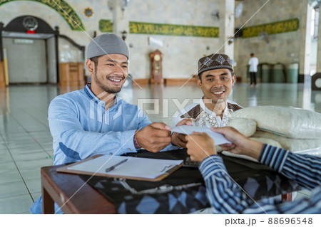 muslim man giving zakat charity for eid mubarak at the mosque muslim man giving zakat charity for eid mubarak at the mosque 88696548