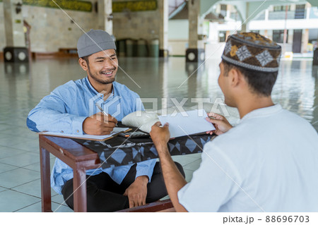 muslim man giving zakat charity for eid mubarak at the mosque muslim man giving zakat charity for eid mubarak at the mosque 88696703