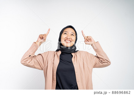 Smiling hijab woman with finger pointing up hand gesture Smiling hijab woman with finger pointing up hand gesture 88696862