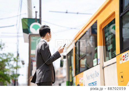 ビジネスマン　イヤホン　バス停　バス 88702059