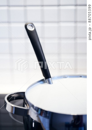 The process of making yogurt. Milk is heated and fermented by bacteria. Milk in a pot on the stove. Vertical photo. 88705399