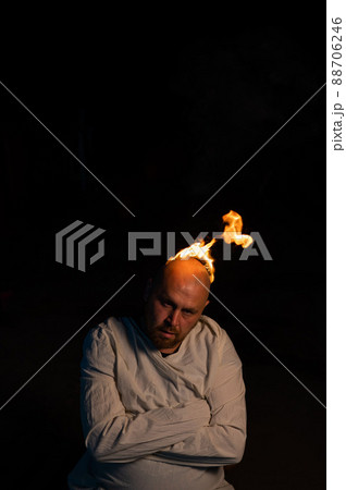 Bald man in a straitjacket with a burning head on a dark background. 88706246