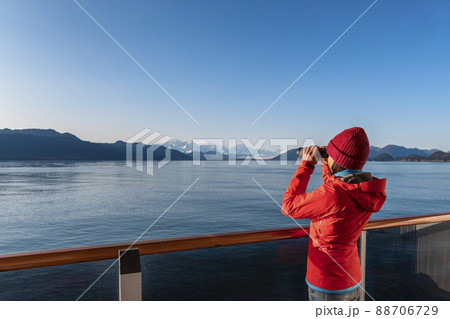 Vacation adventure. Alaska Glacier Bay cruise ship passenger looking at Alaskan mountains with binoculars exploring Glacier Bay National Park, USA. Woman on travel Inside Passage enjoying view Vacation adventure. Alaska Glacier Bay cruise ship passenger looking at Alaskan mountains with binoculars exploring Glacier Bay National Park, USA. Woman on travel Inside Passage enjoying view 88706729