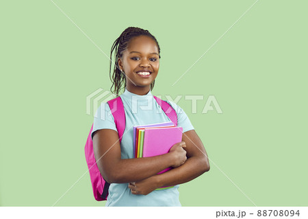 Smiling dark skinned female student with backpack and textbooks on light green background. Smiling dark skinned female student with backpack and textbooks on light green background. 88708094