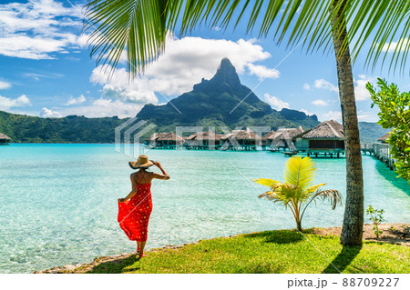 Tahiti travel holiday luxury hotel vacation tourist woman walking on Bora Bora island beach with view of Mt Otemanu in French Polynesia. High end resort with overwater bungalows villas 88709227