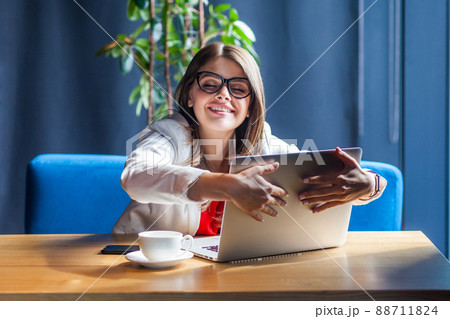 Portrait of happy satisfied beautiful stylish brunette young woman in glasses sitting and hug her favorite laptop with love and toothy smile. indoor studio shot, cafe, office background. 88711824