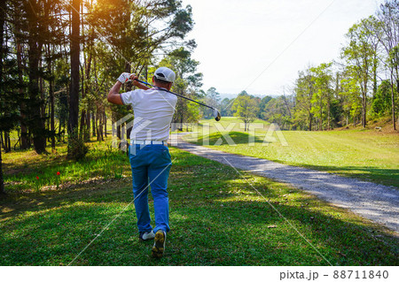 Golfer playing golf in the evening golf course, on sun set evening time. Man playing golf on a golf course in the sun. 88711840