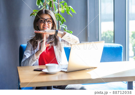 Time out. Portrait of beautiful brunette young woman in glasses sitting, looking at camera and want to have more time or break to rest. indoor studio shot, cafe, office background. Time out. Portrait of beautiful brunette young woman in glasses sitting, looking at camera and want to have more time or break to rest. indoor studio shot, cafe, office background. 88712038
