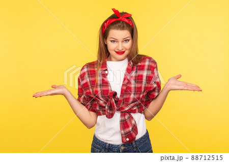 I'm confused, don't know answer. Portrait of puzzled uncertain pinup girl in checkered shirt and headband raising hands in bewilderment having doubts, not sure about choice. retro 50's style, isolated 88712515