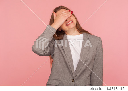 Don't want to look. Portrait of displeased young woman in business suit covering eyes with hand, her face expressing disgust gross shame, scared to watch. studio shot isolated on pink background 88713115