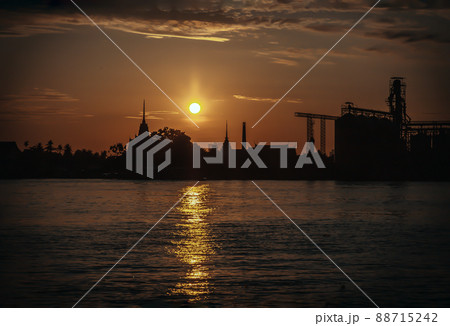 Gorgeous scenic of Thai temple silhouettes and Industrial factory along Chao phraya river over sun at sunrise. Gorgeous scenic of Thai temple silhouettes and Industrial factory along Chao phraya river over sun at sunrise. 88715242