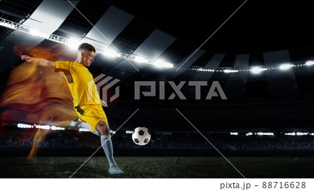 Professional football or soccer player in action on stadium with flashlights, kicking ball for winning goal. Concept of sport, competition, motion, overcoming. 88716628