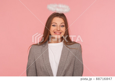 Portrait of optimistic joyful businesswoman in suit jacket with angelic beautiful appearance and halo over her head smiling at camera, looking obedient. indoor studio shot isolated on pink background Portrait of optimistic joyful businesswoman in suit jacket with angelic beautiful appearance and halo over her head smiling at camera, looking obedient. indoor studio shot isolated on pink background 88716847