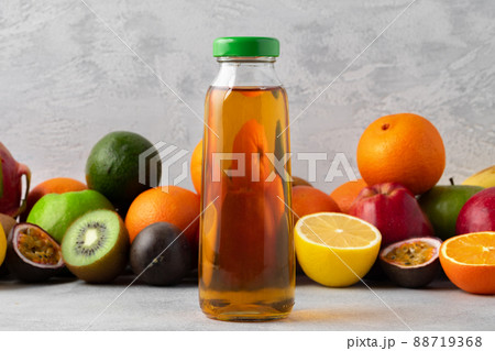 Various fruits and freshly squeezed fruits juice in bottle on gray background Various fruits and freshly squeezed fruits juice in bottle on gray background 88719368