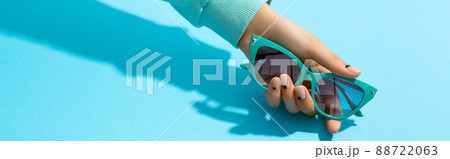 Womans hand holding sunglasses over blue background 88722063