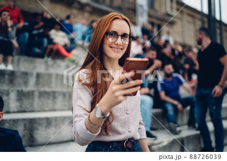 Happy Caucasian woman with red hair using smartphone technology Happy Caucasian woman with red hair using smartphone technology 88726039