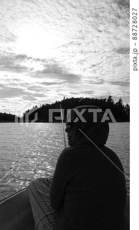 Black and white photo of a woman from behind, resting while fishing 88728027