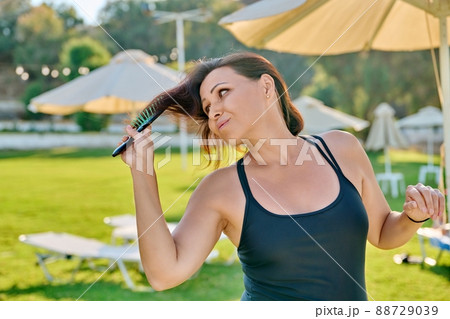Mature beautiful woman in swimsuit relaxing in summer, combing her hair with comb 88729039