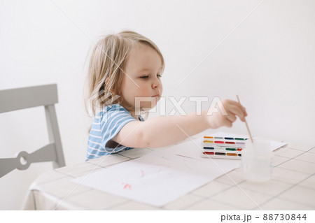 Child painting and drawing with watercolor paint at white table. Development of creative potential in children.  88730844