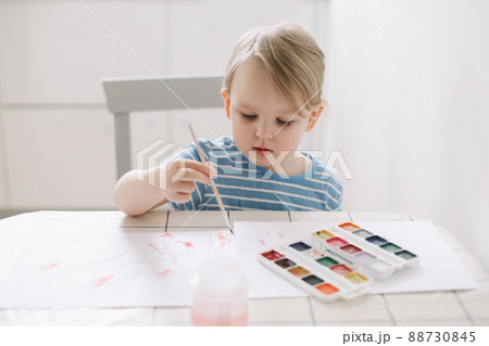 Child painting and drawing with watercolor paint at white table. Development of creative potential in children.  88730845