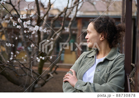 Confident mature woman gardener enjoying an early spring day standing in her botany garden against the flowering fruit trees background Confident mature woman gardener enjoying an early spring day standing in her botany garden against the flowering fruit trees background 88730878