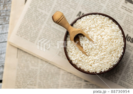 Uncooked Carnaroli risotto rice in bowl and wooden scoop. 88730954