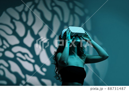 Girl in wireless device watching virtual reality in dark against the pattern background 88731487