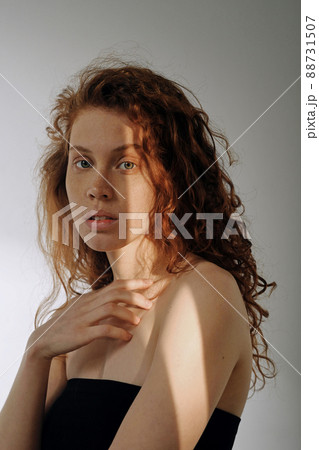 Portrait of young girl with red wavy hair looking at camera isolated on grey background 88731507