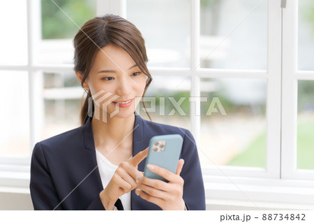 スマートフォンを持った女性　スーツ 88734842