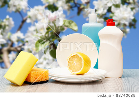Bottles of dishwashing liquid, plates and sponges on natural background. 88740039