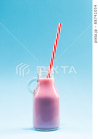 Strawberry milk shake pitcher with straw on blue background. 88741054