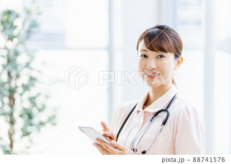 施設内でスマホを操作する医療従事者の女性 施設内でスマホを操作する医療従事者の女性 88741576