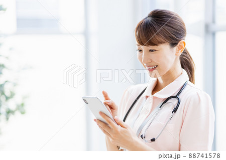 施設内でスマホを操作する医療従事者の女性 88741578