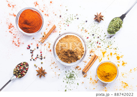 Variety of spices and herbs in spoons and bowls on white background. Top view. Cooking ingredients and condiments concept. Variety of spices and herbs in spoons and bowls on white background. Top view. Cooking ingredients and condiments concept. 88742022
