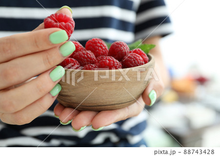 Woman holding wooden bowl with raspberries, cloce up Woman holding wooden bowl with raspberries, cloce up 88743428