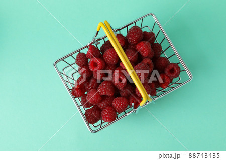 Red juicy raspberries in a shopping basket on a menthol background Red juicy raspberries in a shopping basket on a menthol background 88743435
