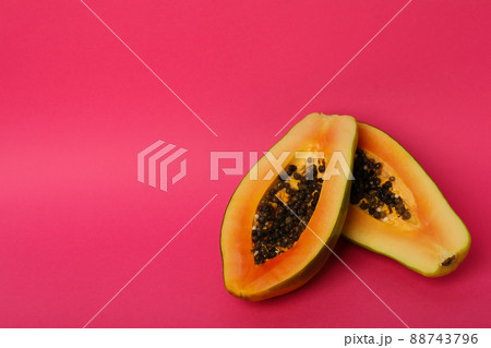 Halves of ripe papaya on pink background Halves of ripe papaya on pink background 88743796