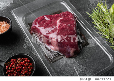 Vacuum black plastic pack with rump beef meat cut, on black dark stone table background 88744724