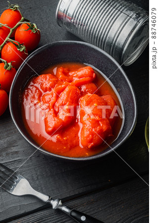 Whole canned tomatoes, on black wooden table background 88746079