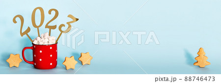 Christmas or New Year 2023 banner. Red mug of cocoa with marshmallows and golden numbers 2023, copy space 88746473
