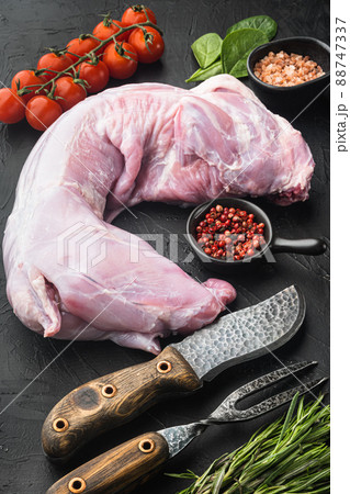 Fresh raw rabbit with olive oil, rosemary, peppers , on black stone background Fresh raw rabbit with olive oil, rosemary, peppers , on black stone background 88747337