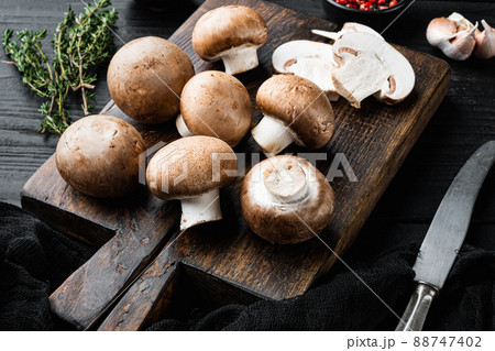 Brown champignons mushroom, on black wooden table background Brown champignons mushroom, on black wooden table background 88747402