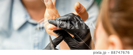 Manicure painting art. Manicure master drawing on the nail tip with a thin brush, close up Manicure painting art. Manicure master drawing on the nail tip with a thin brush, close up 88747676