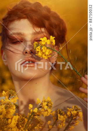 Young fashion model portrait with ginger hair and blue eyes in yellow rapeseed field Young fashion model portrait with ginger hair and blue eyes in yellow rapeseed field 88750032