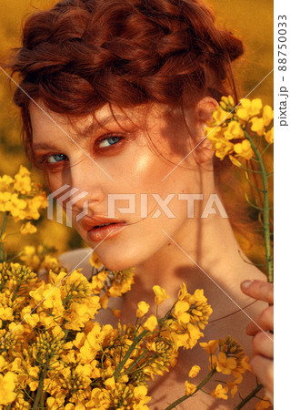 Young fashion model portrait with ginger hair and blue eyes in yellow rapeseed field Young fashion model portrait with ginger hair and blue eyes in yellow rapeseed field 88750033