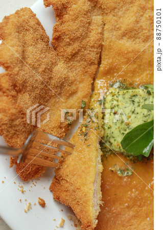 Homemade breaded chicken schnitzel with melting salted butter with herbs and a fork Homemade breaded chicken schnitzel with melting salted butter with herbs and a fork 88750101