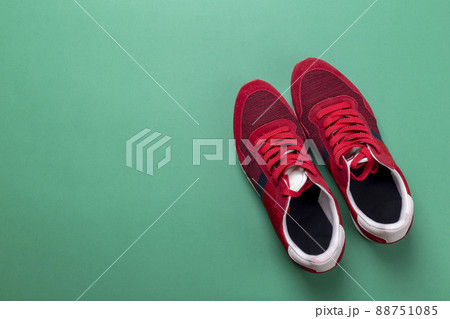 New unbranded running sneaker or trainer on green background. Men's sport footwear. 88751085